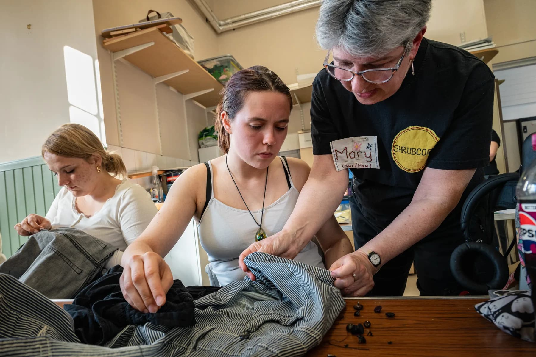Mary Morton, organizer of SHRUB COOP’s Repair What You Wear group, helps Zag, one of the group attendees, with her project. Mary says that what makes SHRUB stand out over other textile and environmental activists is that they educate about the dangers of fast fashion while also teaching to mend, something other groups don’t do. Due to quickly changing fashion trends, textiles are being made of materials that are worse for the environment, but they are also ending up in landfills at alarming rates. Repairing what you already own, rather than buying new, not only helps people with limited resources, says Mary, but also keeps the environment safe.