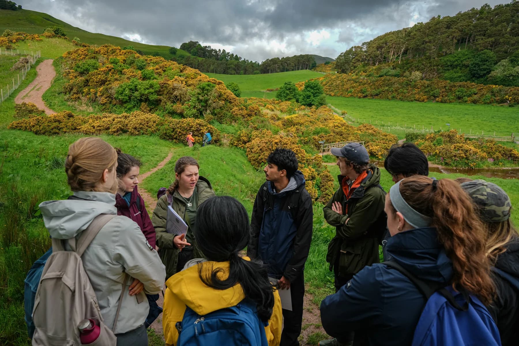 A group of students from the University of Edinburgh are led by a PhD student, Alice, to collect data for research on native grasses at Rullion Green Wood. The grasses help indicate the health of young trees planted by the university on the formerly developed land.